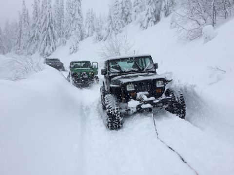 1995 Jeep Wrangler - Multiple Jeeps navigate a snow-covered trail, with one vehicle being towed.