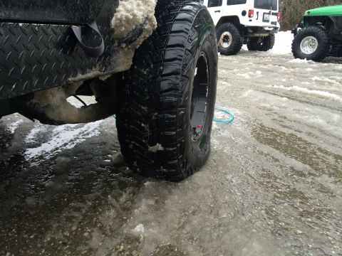 1995 Jeep Wrangler - Multiple Jeeps parked on a snowy, icy surface, focusing on the rear tire of one vehicle.