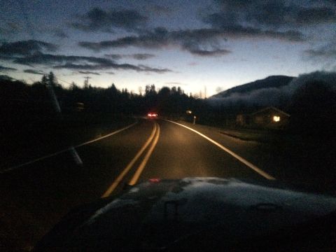 1995 Jeep Wrangler - Driving on a two-lane road as twilight descends, with a distant house and approaching clouds.