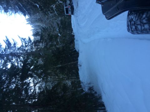 1995 Jeep Wrangler - A white SUV navigates a snow-covered road winding through a dense forest.