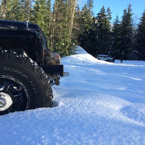 1995 Jeep Wrangler - A black 1995 Jeep YJ is partially submerged in snow, with another white Jeep visible in the distance.