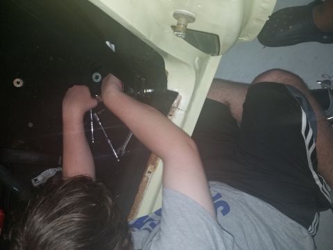 1971 Ford Mustang - A person is working on the seat belt hardware inside a car.