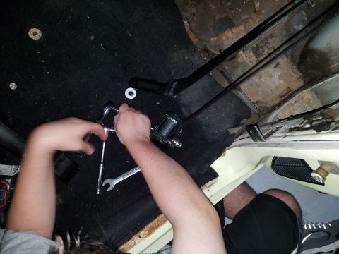1971 Ford Mustang - A person works on a seat belt mechanism inside a vehicle's interior.