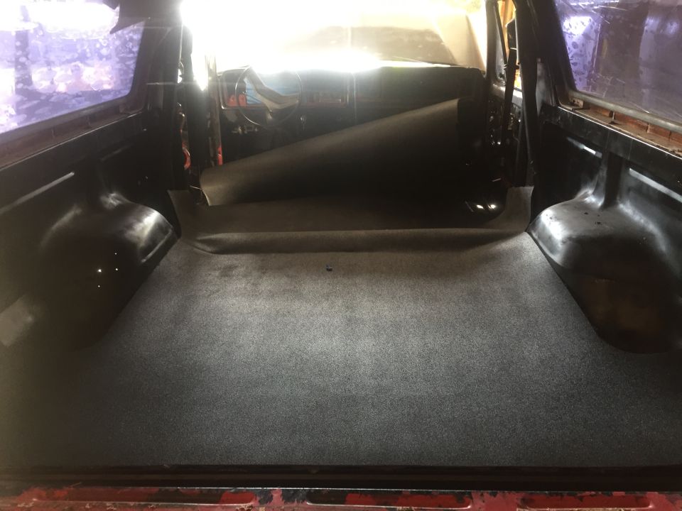1978 Ford Bronco interior cargo area with grey carpet and a rolled-up mat