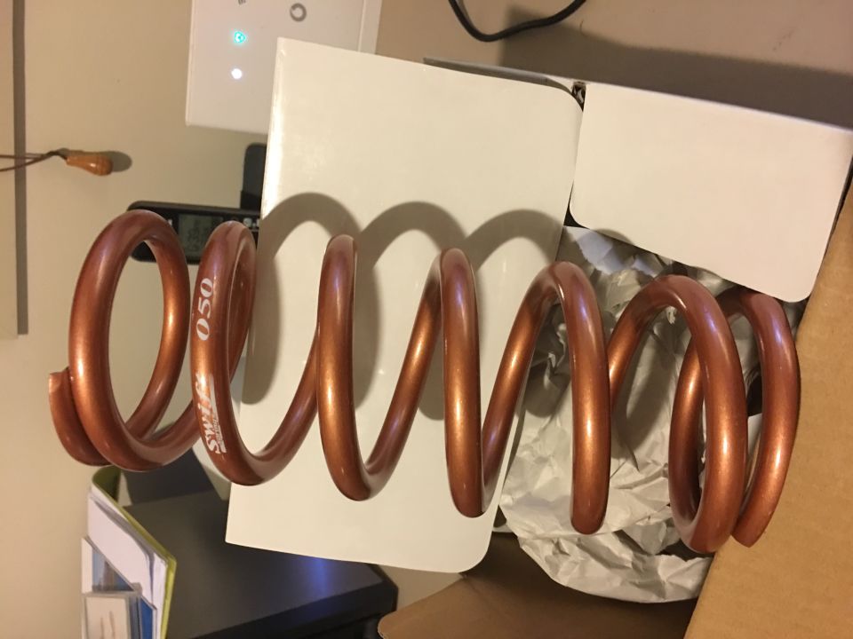Copper coil spring with "Swift 050" text on it, sitting in a box