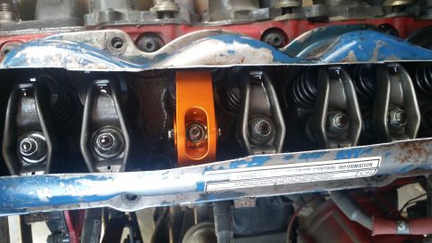 1981 Ford Bronco - Close-up view of an engine's valve train, highlighting an aftermarket orange roller rocker arm.