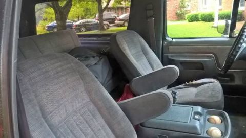1990 Ford Bronco - The interior of a 1990 Ford Bronco features cloth seats and a center console with cup holders.