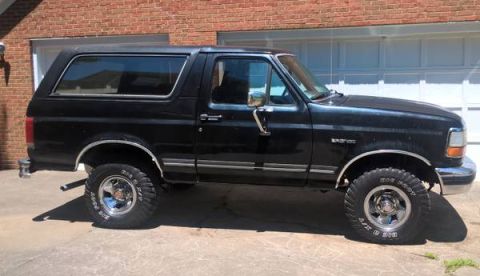 1990 Ford Bronco - Side view of a black Ford Bronco, model year 1990, with chrome wheels.