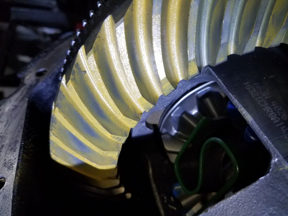 Close-up of differential gears with yellow teeth and blue markings. Part number visible