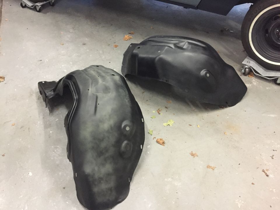 Two black plastic fender liners on a concrete floor