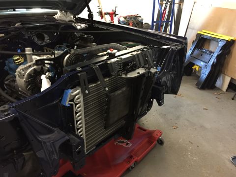 2001 Ford Crown Victoria - Front end of a dark blue vehicle undergoing repairs, showing the engine bay, radiator, and AC condenser.