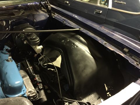 2001 Ford Crown Victoria - Close-up view of a blue engine bay, showing the brake master cylinder and inner fender. A second vehicle is partially visible in the backgr…