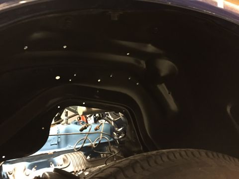 2001 Ford Crown Victoria - View into a vehicle's wheel well reveals a blue engine block and part of a tire.