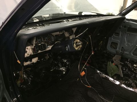 2001 Ford Crown Victoria - The interior of a car is shown with the dashboard disassembled, revealing exposed wiring and sound-dampening material on the floor.