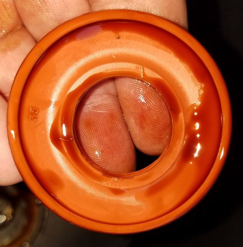 2000 Ford Crown Victoria - Close-up of an orange rubber gasket with oil, revealing finger prints and a numerical marking.