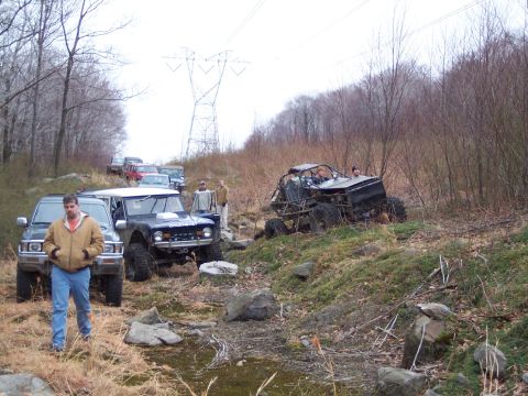 1978 Ford Bronco - A group of off-road vehicles are seen on a trail, with one vehicle appearing to be a Ford Bronco.