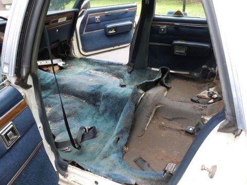 2001 Ford Crown Victoria - The interior of a white sedan shows significant wear and tear on the carpet and flooring.