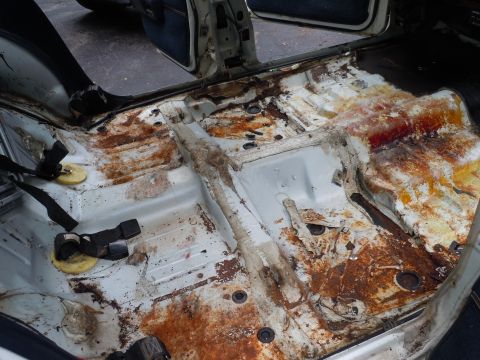2001 Ford Crown Victoria - The interior floor of a vehicle shows significant rust and deterioration.