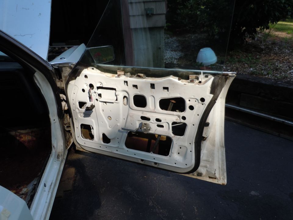 Car door with interior panel removed, showing internal mechanisms. Hood is up