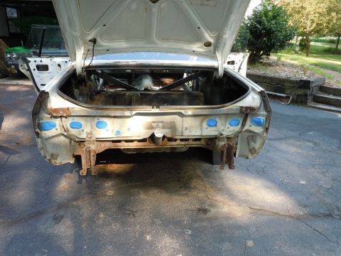 2001 Ford Crown Victoria - The rear of a car is shown with the trunk open, revealing a stripped-down bumper area and exposed metal.