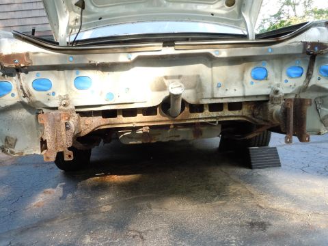 2001 Ford Crown Victoria - The rear of a vehicle shows a heavily rusted bumper support structure with blue tape on some mounting holes.