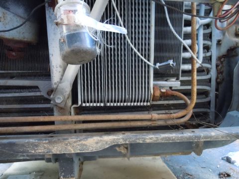 2001 Ford Crown Victoria - Close-up view of a vehicle's front end, revealing the radiator, condenser, and a jury-rigged container collecting fluid.