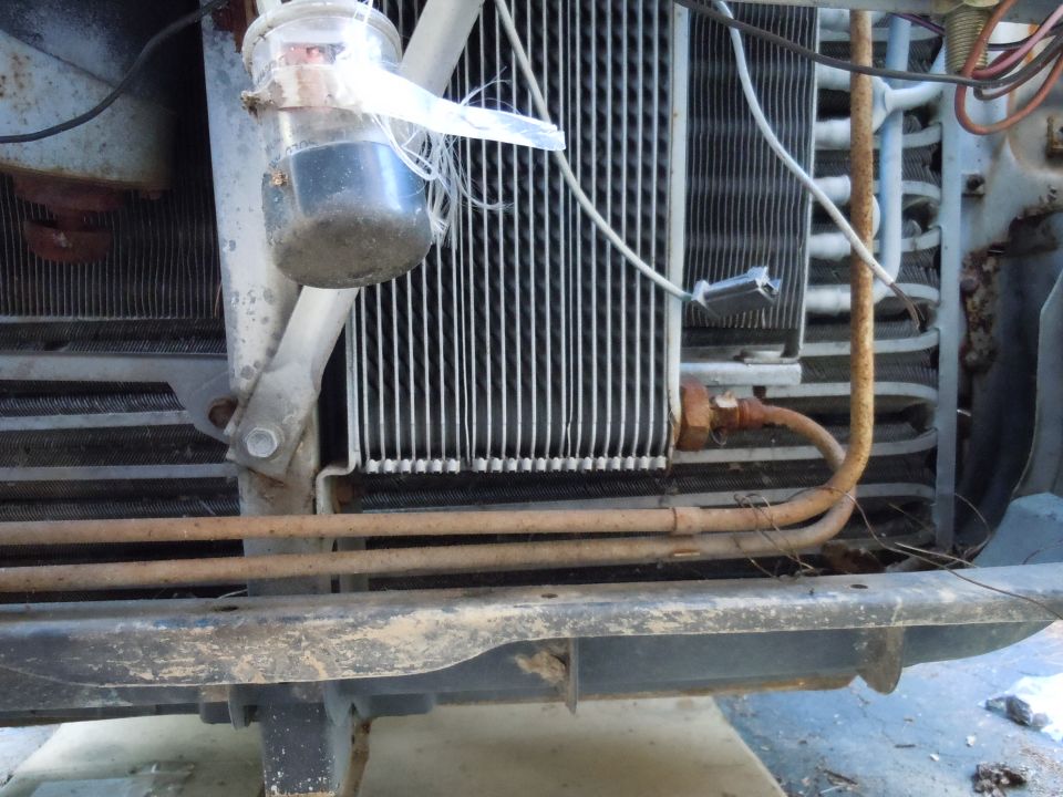 Front end of a vehicle showing radiator, condenser, and a makeshift fluid collector