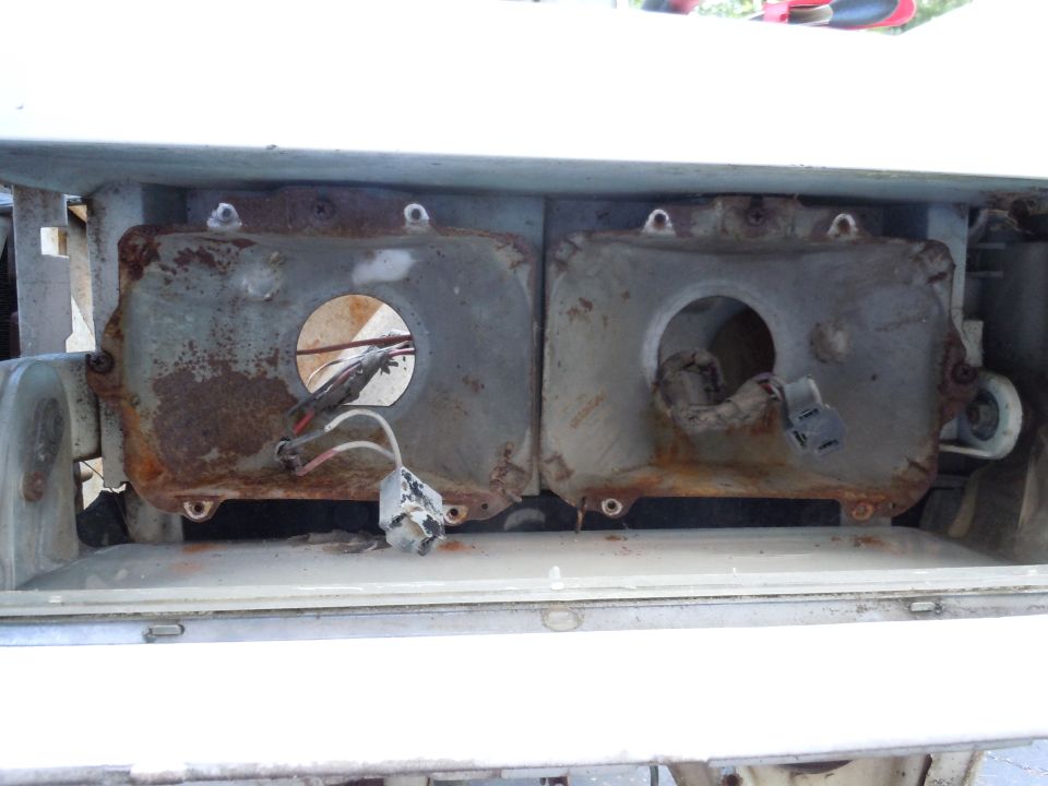 Two rusted headlight housings with exposed wiring and connectors