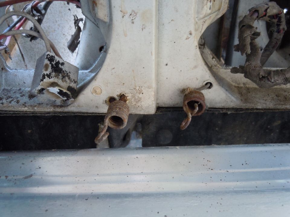 Two rusted springs attached to white plastic with exposed wiring