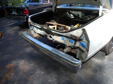 2001 Ford Crown Victoria - Damaged rear end of a white car, with a black car parked behind it.