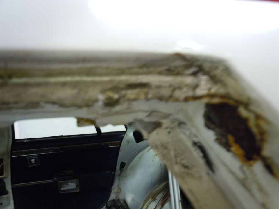 Interior door panel and rusted roof edge of a white vehicle