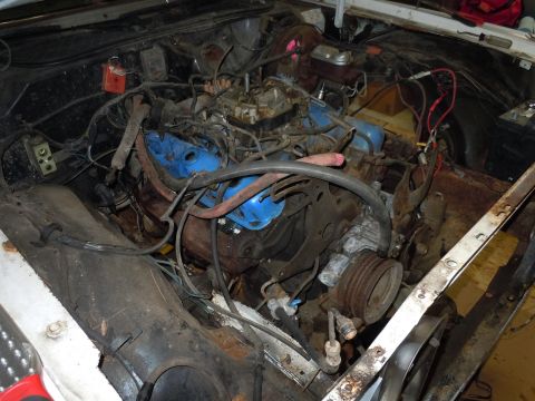 2001 Ford Crown Victoria - The engine bay of a vehicle, showing the engine block, carburetor, and various hoses and wires.