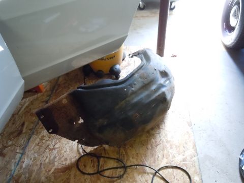 2001 Ford Crown Victoria - A detached fender liner rests on a plywood surface, showing signs of rust and wear.