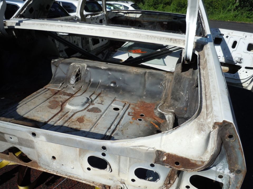 Stripped car trunk interior showing rusted metal floor and body panels