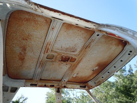 2001 Ford Crown Victoria - Interior view of a heavily rusted car roof structure against a blue sky.