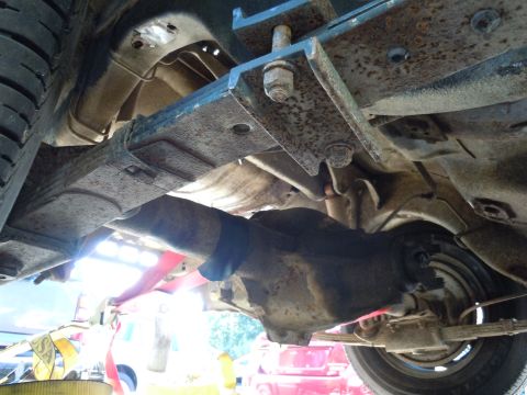 2001 Ford Crown Victoria - Close-up view of the undercarriage, focusing on the rear axle and suspension system of a vehicle.