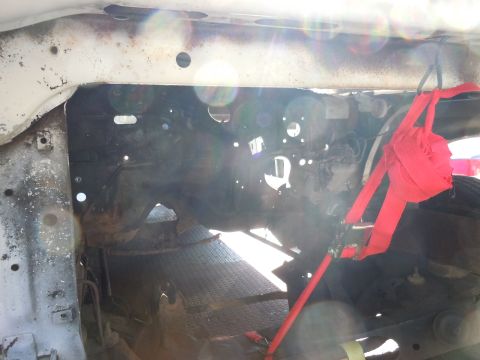 2001 Ford Crown Victoria - The engine bay of a vehicle, showing structural components and a red tie-down strap securing a tire.