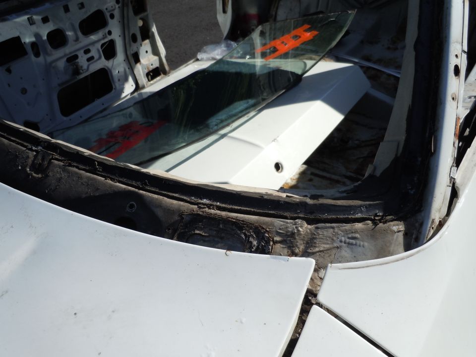 Interior of dismantled vehicle, showing exposed frame and broken windshield