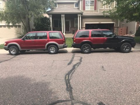 2000 Ford Explorer - Two Ford Explorers are parked on a residential street in front of a house.