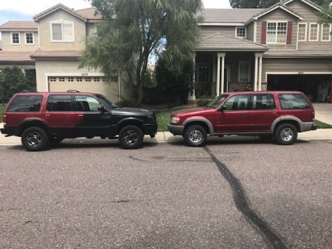 2000 Ford Explorer - Two Ford Explorers are parked on a street in front of suburban houses, one with a two-tone paint job.