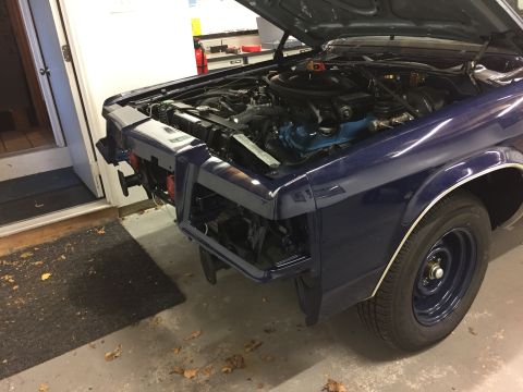 2001 Ford Crown Victoria - Front view of a dark blue sedan undergoing repairs in a garage, showing the engine bay.