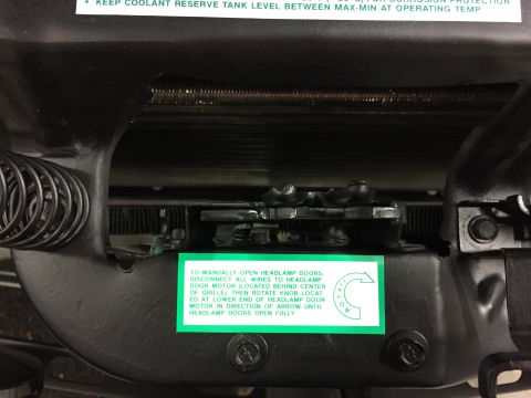 2001 Ford Crown Victoria - Instructions for manually opening headlamp doors are visible on a green sticker attached to the vehicle's mechanism.