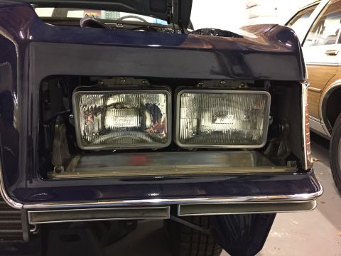 2001 Ford Crown Victoria - Front view of a car with its hood open, revealing the headlight assembly and part of the engine bay.