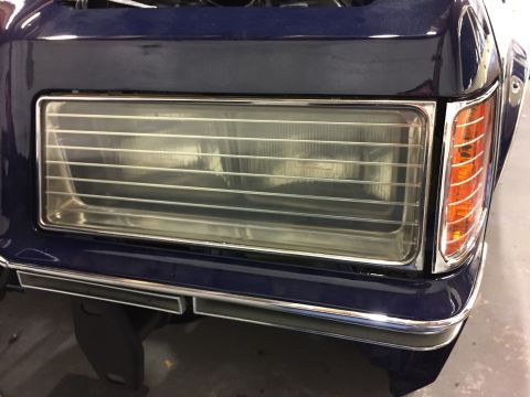 2001 Ford Crown Victoria - The front corner of a dark blue vehicle, showing the headlight and amber turn signal.