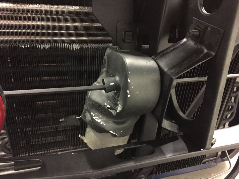 Close-up of a damaged black plastic fan shroud in front of a vehicle's radiator
