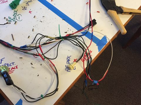 2001 Ford Crown Victoria - A complex wiring harness is spread out on a table, marked with labels and accompanied by tools.