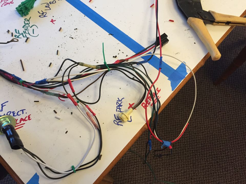 Wiring harness laid out on a white surface with handwritten labels and a pair of wire cutters
