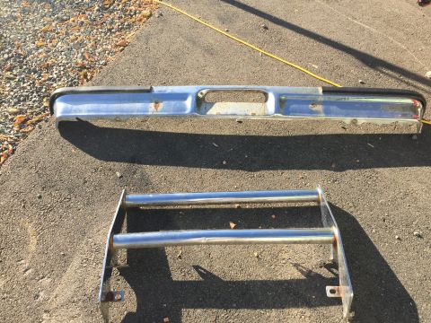 1979 Ford Bronco - Two chrome vehicle parts, a bumper and a bull bar, are displayed on the ground.