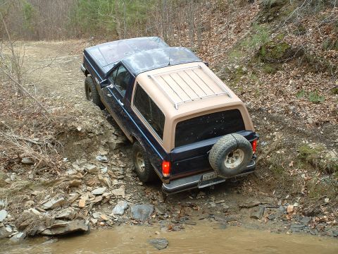 1987 Ford Bronco - This 1987 Ford Bronco navigates a challenging off-road course with a two-tone paint scheme and spare tire mounted on the rear.