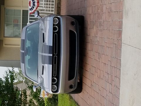 1994 Ford Bronco - Silver Dodge Challenger with black racing stripes parked on a brick driveway.
